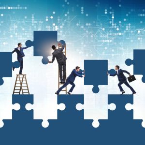 A team of people in suits work together to assemble a larger than life illustrated puzzle.